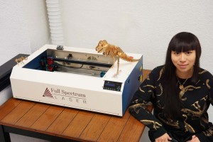 Fab Lab Cathy Chen Outreach Director poses with their 45W Laser Cutter from Full Spectrum Engineering